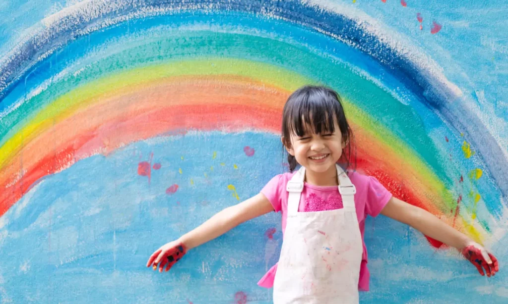 asian little girl is painting the colorful rainbow