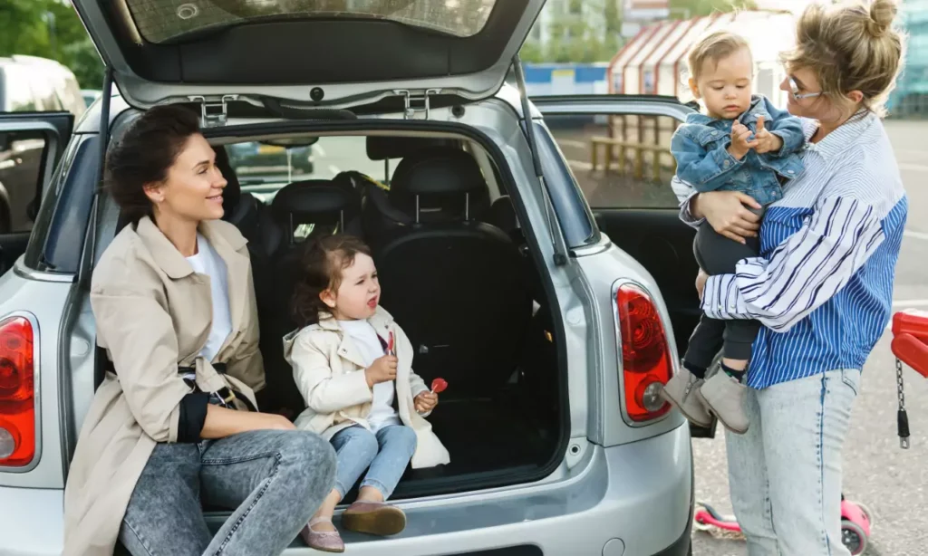 happy women and their beautiful kids beside a car